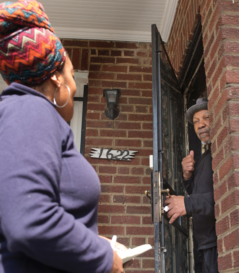 a man leans out of his front door to speak to a woman