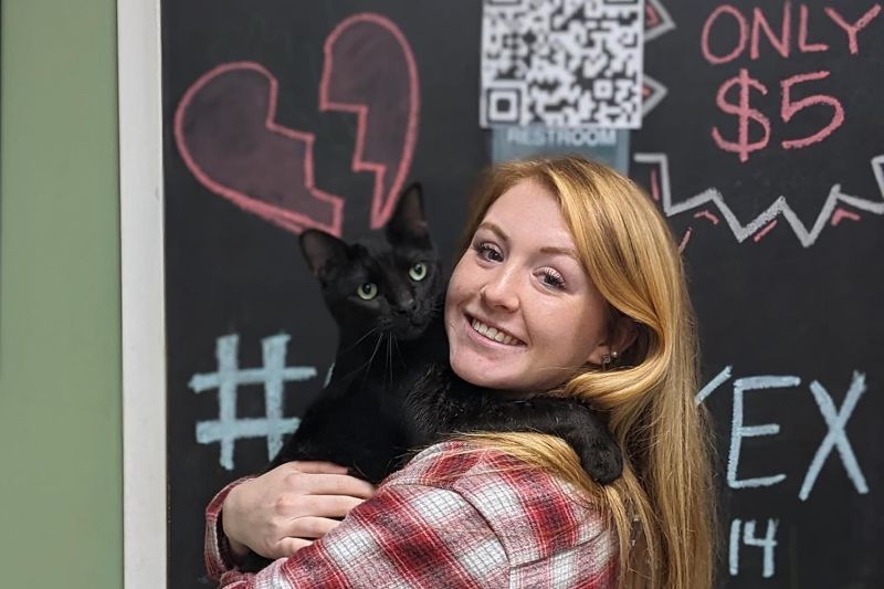 Photo of a woman holding a black cat she just adopted.
