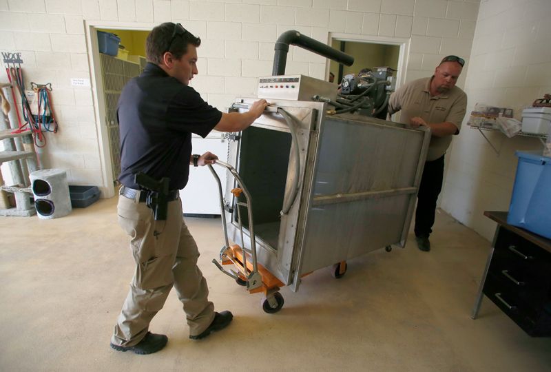 two men moving a gas chamber
