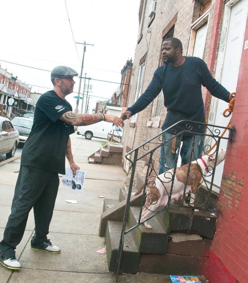a man extends his hand to shake the hand of a man standing on his doorstep