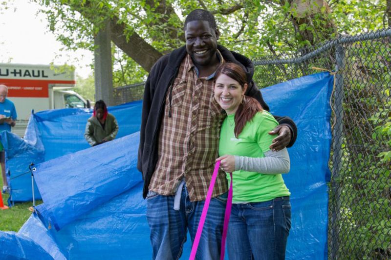 a woman and man pose together in front of blue tarps