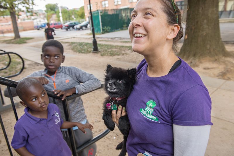 a woman holds a dog while two children look on