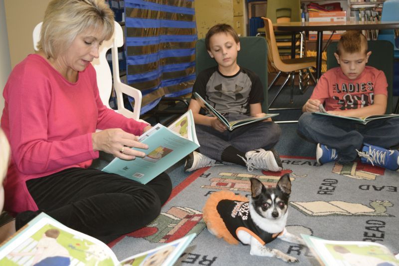a woman reading to children while a dog looks on