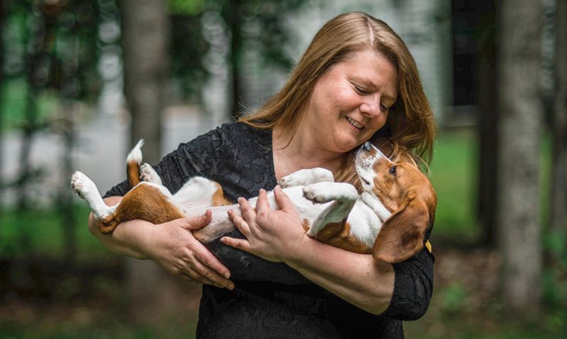 a woman cradles her dog in her arms