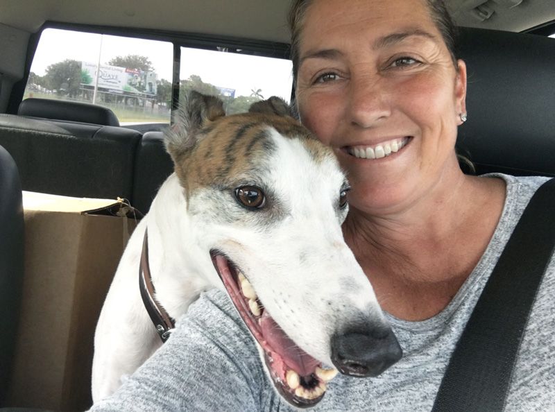 A woman posing with her rescue greyhound