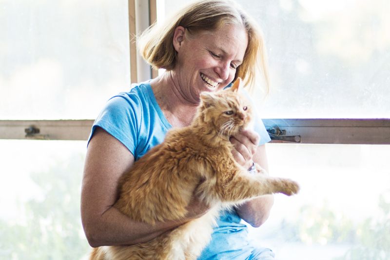 a smiling woman holding a large orange cat