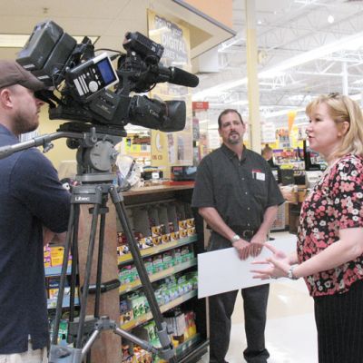 a woman being interviewed in front of a camera in the grocery store