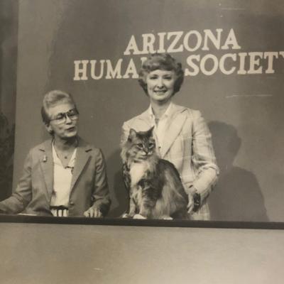 black and white photo of two women presenting a cat on tv