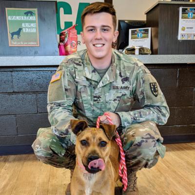 a man in military uniform poses with his shelter dog