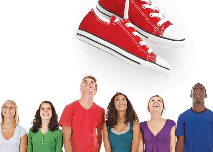 A group of people looking up at a huge pair of shoes
