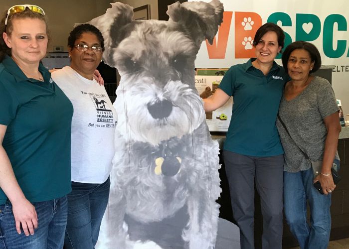 four women gathered around a large cardboard cutout of a dog