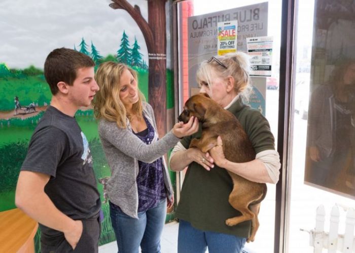 two people talk to a woman holding a puppy